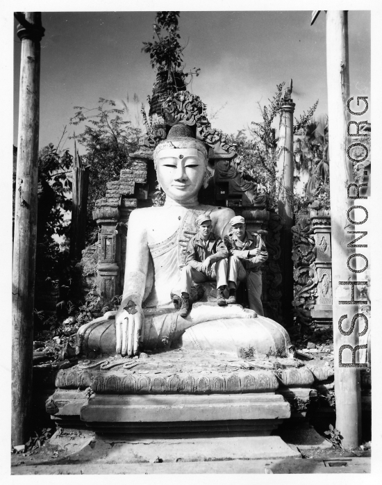 GIs sit on Buddha statue in remains of Buddhist temple in Burma.  During WWII.