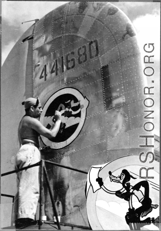 Unknown artist painting "The Wily Wolves" squadron insignia on tail of 24th Combat Mapping Squadron F-7, #441680.