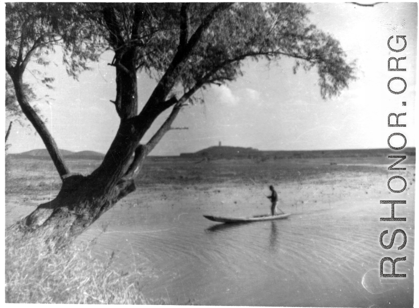 Chinese man standing on a boat in a lake in China during WWII.