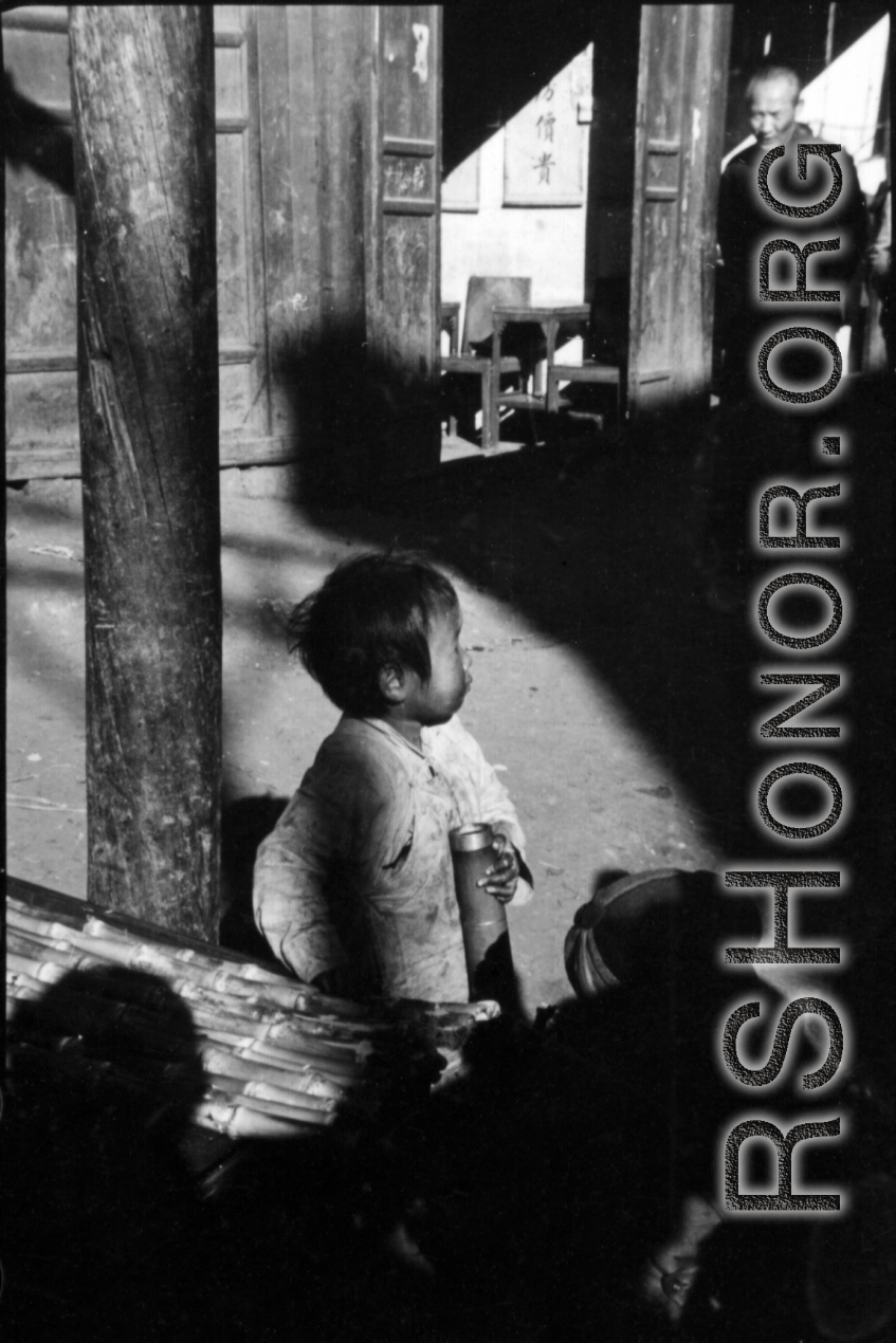 A child holds a bamboo water pipe in China during WWII.