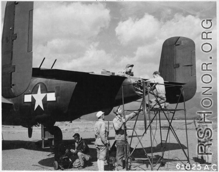 "With Chinese Military Guard Standing Close By, Ground Crew Of The 14Th Air Force Work On A North American B-25, Preparing It For Another Raid On Enemy Installations."  A ground crew of the 341st Bombardment Group does maintenance to the tail gunner position on a B-25, which appears to have already had a field modification, possibly in Chakulia.