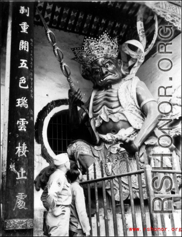 GI looks at temple guards at a Buddhist temple in China during WWII.