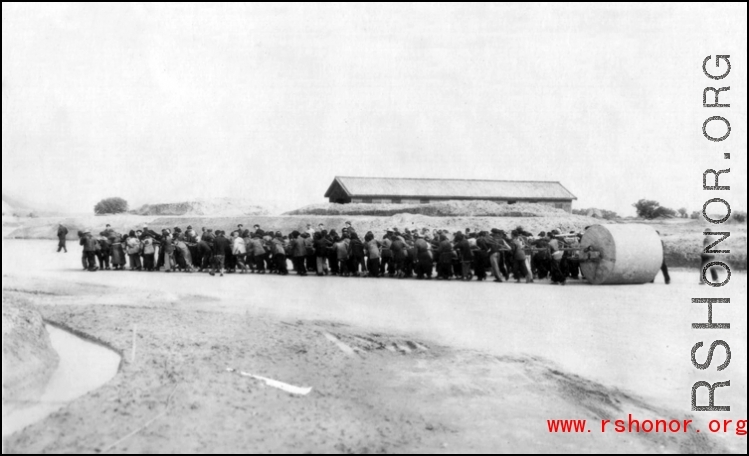 A crew of Chinese civilians pulling a roller at an air base in the CBI. During WWII.