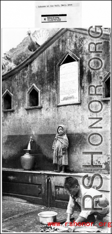 A child at a public well in the Darjeeling, India, area. Readable on the sign above are the words in English "TO THE GLORY OF GOD." During WWII.  Photo from Robert D. Lichty.