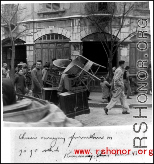 Chinese man carrying furniture in street of Kunming. March 1945.