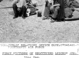 Two local civilians sit on the ground in destroyed Liuzhou after the return of Chinese and American forces on the tails of the Japanese retreat. In WWII.