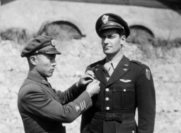 1st Lt. Robert L. Logan stands at attention as ta Chinese Air Force staff officer adjusts his new Chinese Air Force Wings. Lt. Logan received his wings based on his service in CACW, as a leader of the "Spray and Pray Squadron."