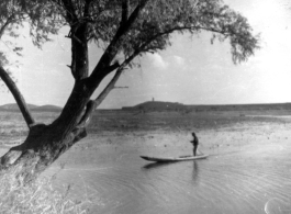 Chinese man standing on a boat in a lake in China during WWII.