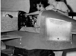 Instrument flying training. Sgt. Kenneth E. Brandon showing Capt. C. C. Wang, Chinese Air force, reactions of setting instruments in link trainer. India.