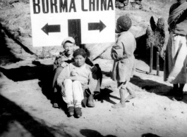 A pipe-smoking GI cuddles a foot-bound Chinese woman against the Burma-China border sign. During WWII.  Image from Emery and Beth Vrana.