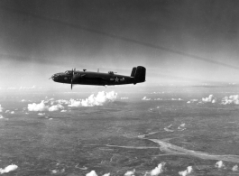 A B-25 Mitchell bomber in flight in the CBI, in the area of southern China, Indochina, or Burma, during WWII.