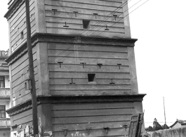 A gun tower fortress in Yunnan province, China, probably in Kunming city, during WWII. Note the desks set up for various kinds of business on the sidewalk in the foreground.