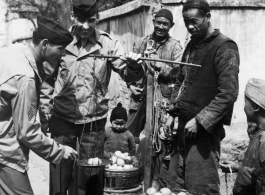 GIs buy citrus from farmers in China during WWII. These might be the amazing regional penggan (椪柑), somewhat similar to a mandarin orange.  Americans and Chinese interact at the market, China.  From the collection of Wozniak, combat photographer for the 491st Bomb Squadron, in the CBI.