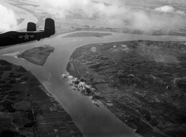 A Mitchell B-25, tail number 444, flies away from a site just bombed in China or Indochina area.