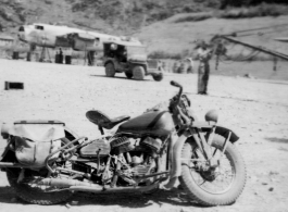 "Lt.Sohl took this cycle with him to every base we serviced. I had never ridden a cycle before and he let me ride it around the revetment one day and I ended up driving right thru the door of the engineering shack and pinned "Rocky" Taurisano against the back wall of the shack. That was the first and last time I ever rode a cycle." Caption courtesy of Elmer Bukey.