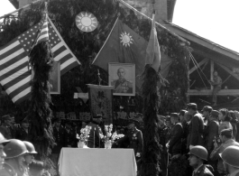 Burma Road dedication ceremony in Kunming, China, on February 4, 1945, during WWII. Review of first convoy (or one of the first convoys) to reach China. General view of the stage and reviewing party, with American and Chinese dignitaries, soldiers, and civilian VIPs. An American band plays, and an honor lines on both sides of the center carpet stand in formation.  Official dignitaries at the ceremony included, on the Chinese side, such figures as General Lung Yun, Governor of Yunnan Province,  Gen. Wang Yu-