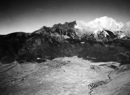 Jade Dragon Snow Mountain (玉龙雪山) with a capping of snow in Yunnan, China, in January as seen from passing American airplane during WWII.  Farm fields and (possibly) rice paddies below.