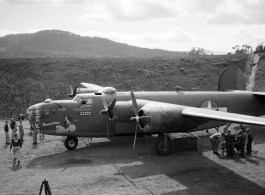 American flyers and mechs gathered around B-24 'Doodlebug' in a revetment in Sichuan, China, likely in preparation for a mission.