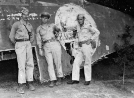 GIs pose against downed aircraft wing. The middle person might be Maj Richard D. Day (李察戴).