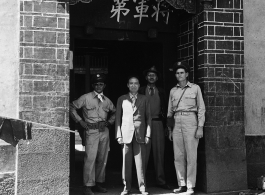 American soldier, KMT solder, and KMT civilians at rally pose for portrait shot. In the suit in the center should be An Zefa (安则法), a highly educated official who had a number of roles in Yunnan during WWII.  These men stand in the gate of an elite residence in Yunnan province, which has been appropriated by Nationalist 5th Corps forces for military purposes--the white paper posted on the door post says the residence is temporary housing for assistant staff for officers, and HQ for an armored unit. The resi