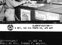 Pre-Christmas scene at the SOS (Service of Supply) PX at APO 627. Cpl Harold L. Graff, Cpl. Ben L. Rohleder, 1st Lt. Frances J. Vesset, and Anna Wong.  December 15, 1944.  Photo by Pfc. Thomas F. Melvin.  Passed by censor Emanuel Goldberg.