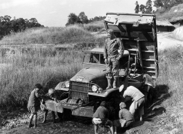 T/5 Theodore E. Eitel directs children in cleaning his Burma Road Engineers truck, after a day of hauling rock for the Kao Tien district of the Burma Road being built from Lungling, China, to meet the Ledo Road at the Burma border.  Yunnan Province on December 1, 1944.   Photo by T/Sgt. Greenberg. B-Detachment, 164th Signal Photographic Company, APO 627.  Passed by William E. Whitten.