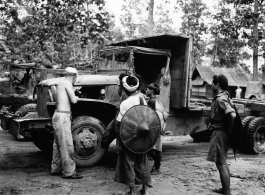 Local men observe as a GI repairs a truck in Burma.  During WWII.  797th Engineer Forestry Company.