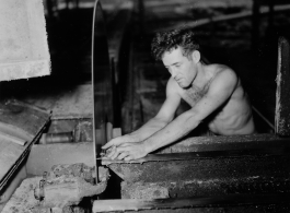 GI of the 797th Engineer Forestry Company in Burma, adjusting saw blade guide in mill.  During WWII.