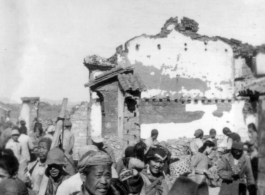 Local people walk by devastated buildings in Yunnan, during WWII.