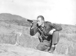 Flyer Ted Simmons playing with pistol on stone bridge at Chanyi (Zhanyi), during WWII.