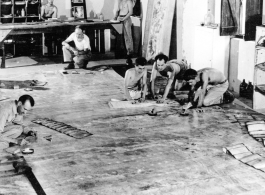 Organizing images on large panels on the floor at photo lab of the 24th Mapping Squadron--cutting and pasting numerous high-resolution aerial images together onto a board to create a wide view.