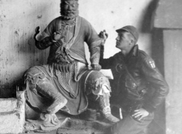 American flyer explore temple and looks at statue at Chanyi (Zhanyi), during WWII.