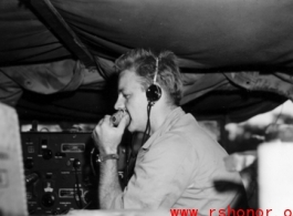 A GI talks into a microphone of a portable radio in the back of a vehicle, during WWII in China.