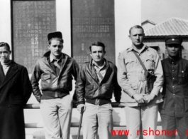 American air men who survived an air incident, with some of the Chinese men who took care of them on the ground. During WWII, in China.  The plaque on the back is commemorating the construction of a local fortress ("青年堡垒").