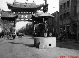 The Golden Horse 金马 archway in Kunming, one of the pair with the Emerald Rooster Archway (金马碧鸡坊) behind the cameraman. A traffic policemen directs traffic from a concrete stand.  In the CBI during WWII.