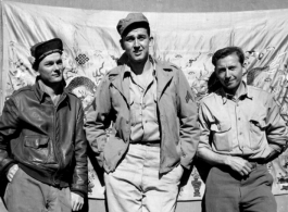 GIs in the CBI, standing in front of an elaborate embroidered silk sheet, during WWII.