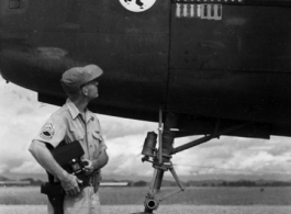 An American aircrew member observes the masking for three new mission symbols on the side of a B-25C at an airbase China. The "Mr. Jiggs" insigne of the 11th Bomb Squadron is visible, as well the previous sixty-three mission symbols.  