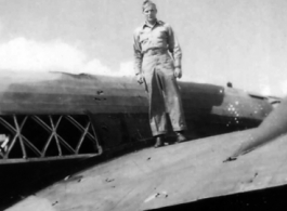 Paul Hunt standing of the wing of a damaged transport plane in the CBI.