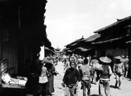 Local people in Yunnan province, China: A town street with drum tower (or bell tower) at the center. During WWII.