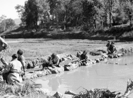 Local people in Yunnan province, China: Women washing clothing in village. During WWII.