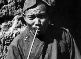 Local people in China: Village man smokes modest pipe, during WWII.