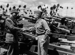 September 29, 1945    Kunming China L to R: Col. Hwang 13th Regt. C. O. shakes hands with Col. Charles Haggerty, American Liaison Officer (M. S.) to Chinese 13th F. A. Regt., with American artillery in the background. During WWII.   Photo by T/4 Henry Allen