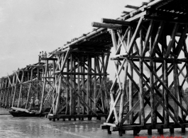 Allies building a wooden trestle bridge across a river in the CBI during WWII.