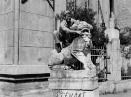 "Stewart, our unit clown" standing on a stone lion near a gate in Yunnan province, China, during WWII.