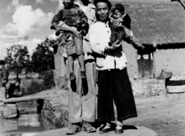 T/5 C. W. Leipnitz and a Chinese family pose together is a small village near Kunming, China, during WWII.