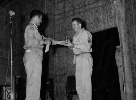 A GI wins a prize during a variety show, while the band Jive-o-Lieps waits to play music in the CBI during WWII. 54th Air Service Group.  Photo from Cal West.