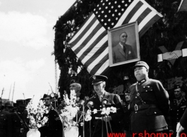 Burma Road dedication ceremony in Kunming, China, on February 4, 1945, during WWII. Review of first convoy (or one of the first convoys) to reach China. General view of the stage and reviewing party, with American and Chinese dignitaries, soldiers, and civilian VIPs. An American band plays, and an honor lines on both sides of the center carpet stand in formation.  Official dignitaries at the ceremony included, on the Chinese side, such figures as General Lung Yun, Governor of Yunnan Province,  Gen. Wang Yu-