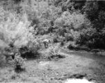 An American soldier fusses over something near a stream in Yunnan province, China, during WWII.