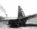 An American airplane destroyed after a Japanese air raid, with another burning in the distance. In China, during WWII.