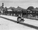 A tired elderly refugee resting on a bridge in Guilin in summer/fall 1944, in front of the Japanese advance.  From the collection of Hal Geer.